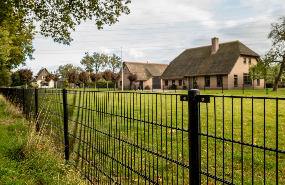 Gitzwart hekwerk rond een weiland in Hierden
